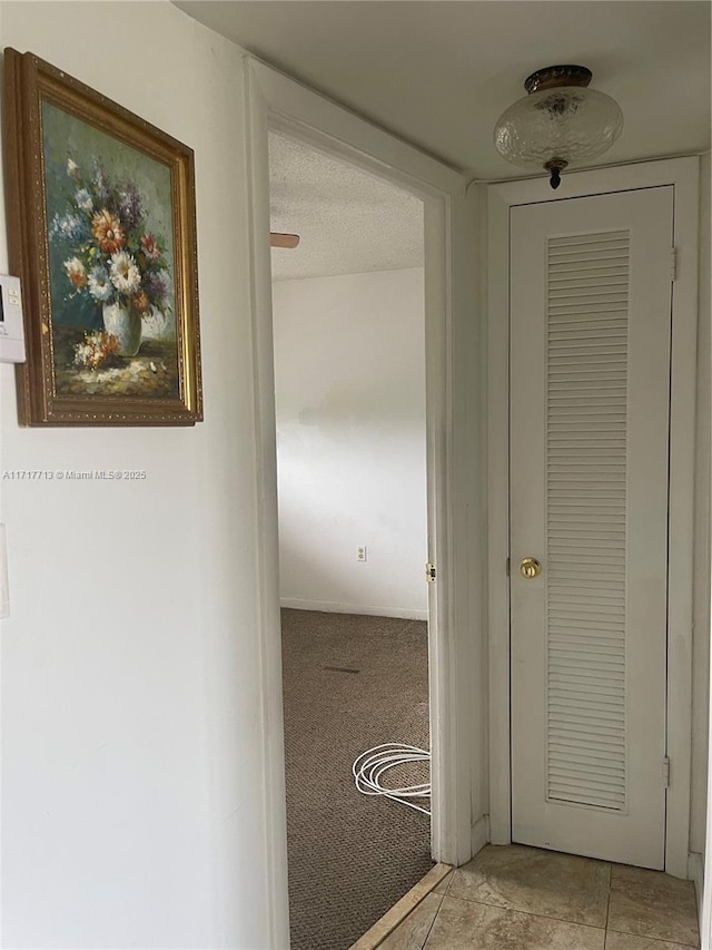 corridor featuring light carpet and a textured ceiling