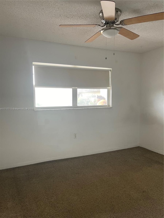 empty room featuring ceiling fan, a textured ceiling, and dark colored carpet