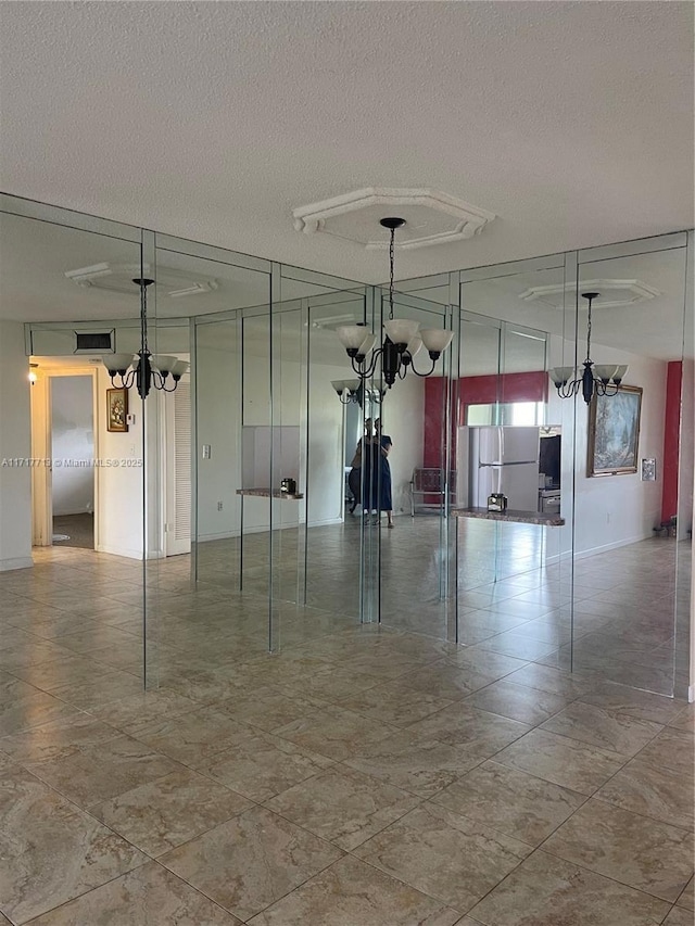 empty room featuring a textured ceiling and a notable chandelier