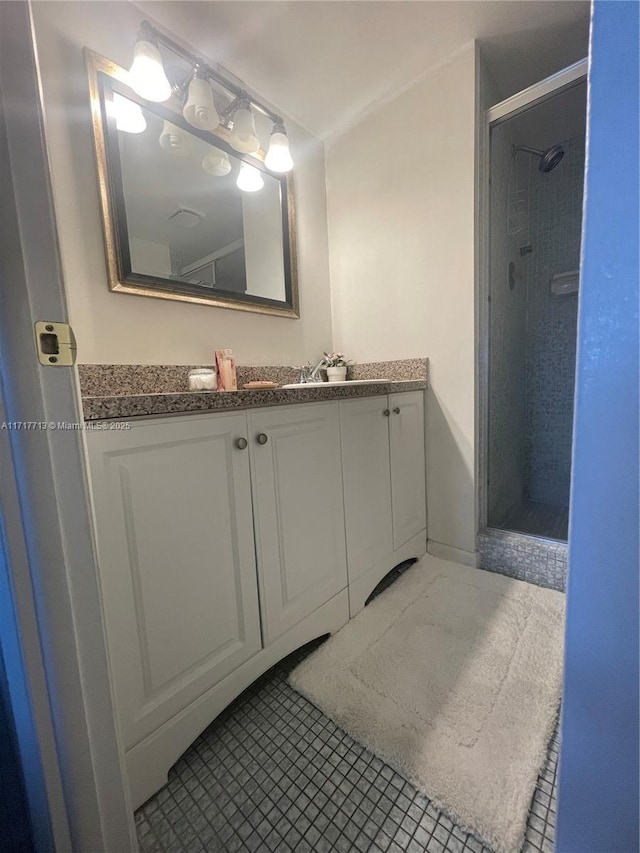 bathroom with a tile shower, vanity, and tile patterned floors