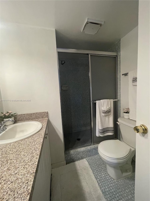 bathroom with tile patterned flooring, vanity, toilet, and a shower with shower door