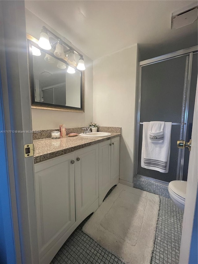 bathroom with tile patterned flooring, vanity, toilet, and a shower with door