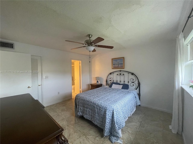 bedroom with a textured ceiling, ensuite bathroom, and ceiling fan