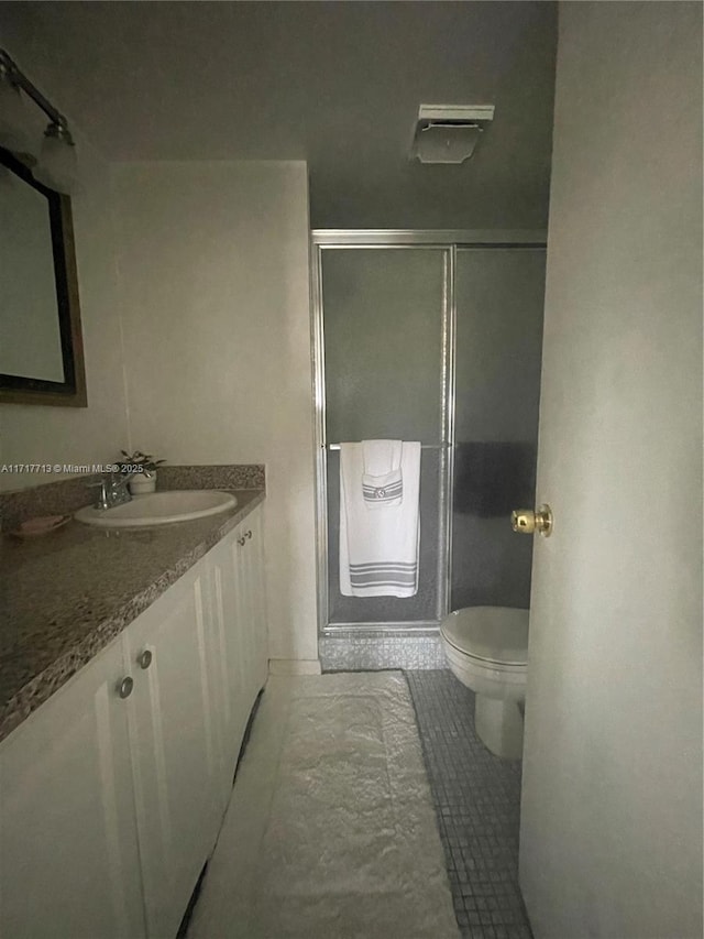 bathroom with tile patterned flooring, vanity, toilet, and a shower with shower door