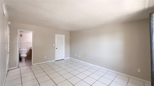 unfurnished bedroom featuring light tile patterned floors and connected bathroom