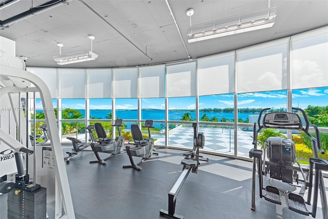 workout area with floor to ceiling windows and a water view