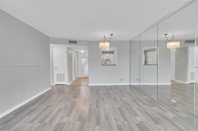 spare room featuring light hardwood / wood-style flooring and a chandelier