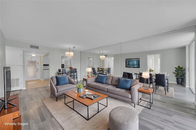 living room with light hardwood / wood-style floors and a chandelier