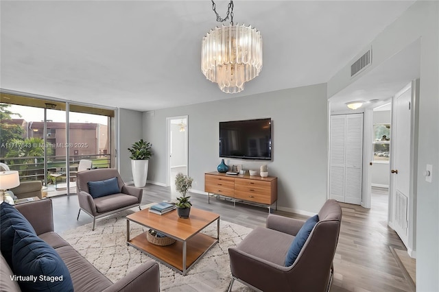 living room featuring floor to ceiling windows, light wood-type flooring, and a chandelier