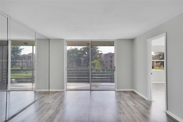 unfurnished room featuring a wall of windows and light wood-type flooring