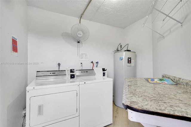 clothes washing area featuring light wood-type flooring, separate washer and dryer, and water heater