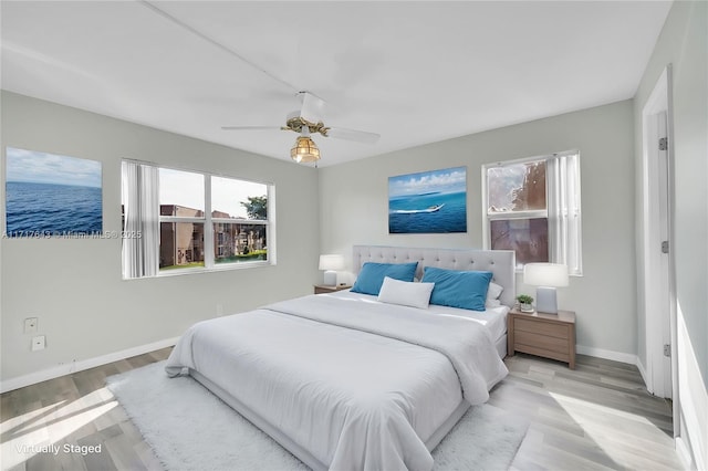 bedroom featuring ceiling fan, a water view, and light wood-type flooring