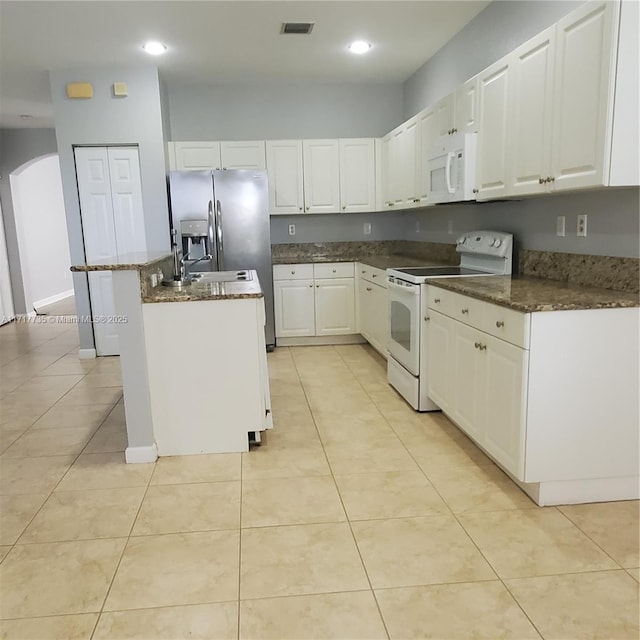 kitchen with a center island, white cabinetry, light tile patterned flooring, and white appliances