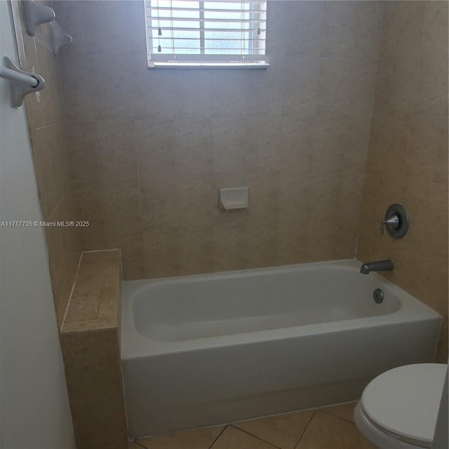 bathroom featuring tile patterned flooring, tiled shower / bath combo, and toilet