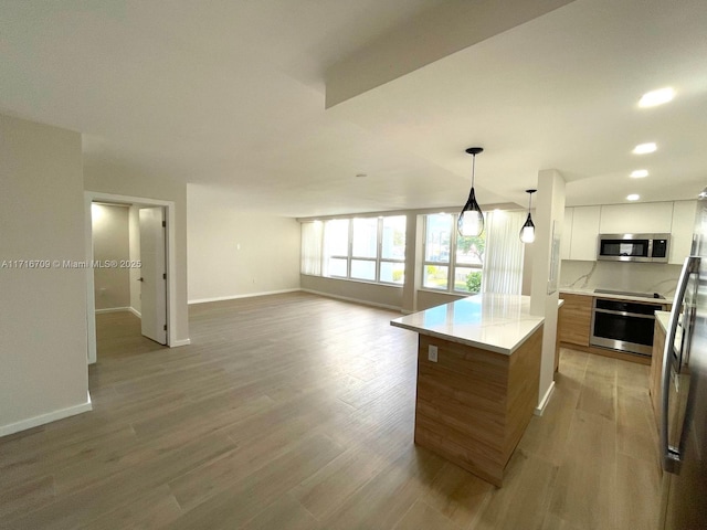 kitchen featuring appliances with stainless steel finishes, a center island, light hardwood / wood-style floors, white cabinetry, and hanging light fixtures