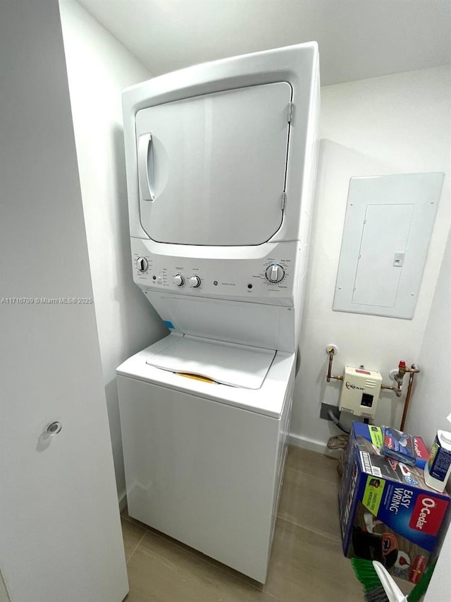 10230 Collins Ave Unit 102, Bal Harbour, FL 33154 - laundry area featuring stacked washer / dryer, electric panel, and light tile patterned flooring
