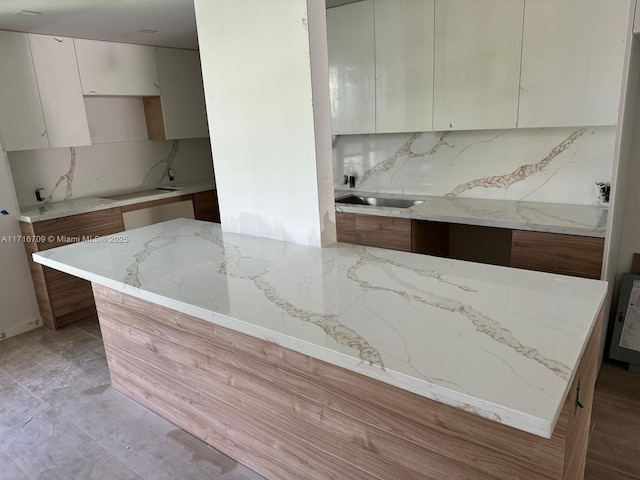 10230 Collins Ave Unit 102, Bal Harbour, FL 33154 - kitchen with tasteful backsplash, a kitchen island, light stone counters, and modern cabinets