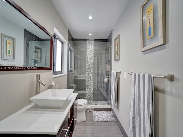 bathroom featuring vanity, toilet, and a shower with shower door