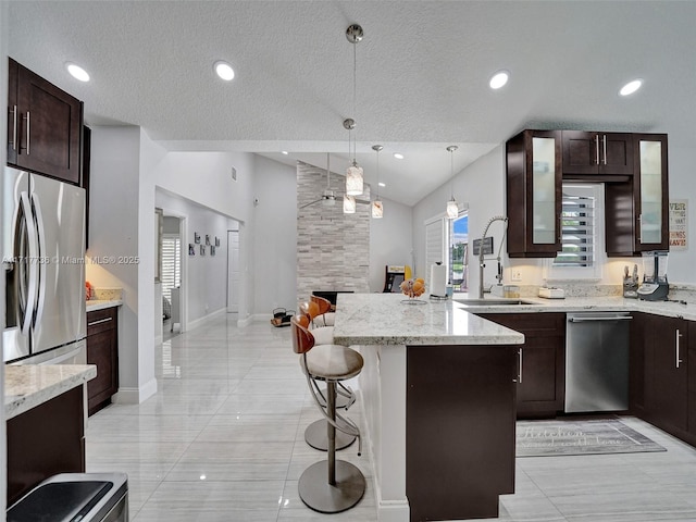 kitchen featuring appliances with stainless steel finishes, a breakfast bar, sink, pendant lighting, and lofted ceiling