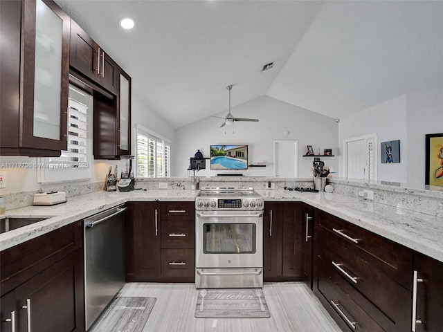 kitchen with light stone counters, dark brown cabinets, stainless steel appliances, vaulted ceiling, and ceiling fan