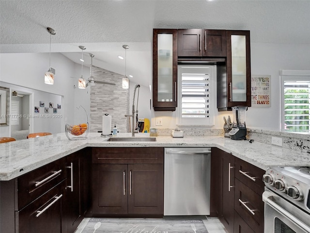 kitchen featuring sink, vaulted ceiling, light stone countertops, kitchen peninsula, and stainless steel appliances