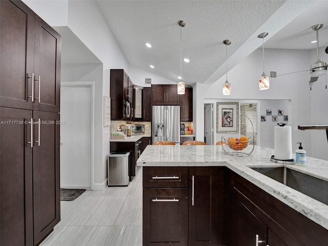 kitchen featuring light stone counters, a textured ceiling, decorative light fixtures, lofted ceiling, and appliances with stainless steel finishes