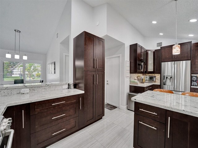 kitchen with light stone countertops, decorative backsplash, hanging light fixtures, and appliances with stainless steel finishes