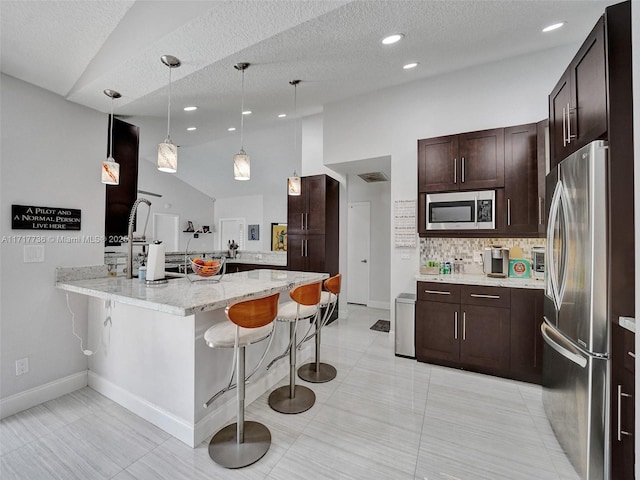 kitchen with kitchen peninsula, a kitchen bar, stainless steel appliances, and vaulted ceiling