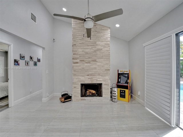 unfurnished living room featuring a tiled fireplace, ceiling fan, high vaulted ceiling, and light tile patterned floors