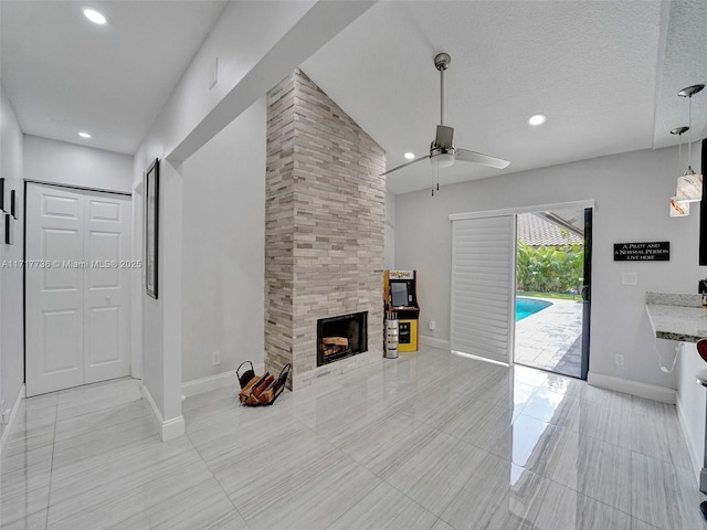 unfurnished living room featuring a tiled fireplace, ceiling fan, and a textured ceiling