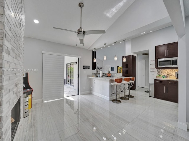 kitchen with backsplash, hanging light fixtures, ceiling fan, a kitchen bar, and kitchen peninsula