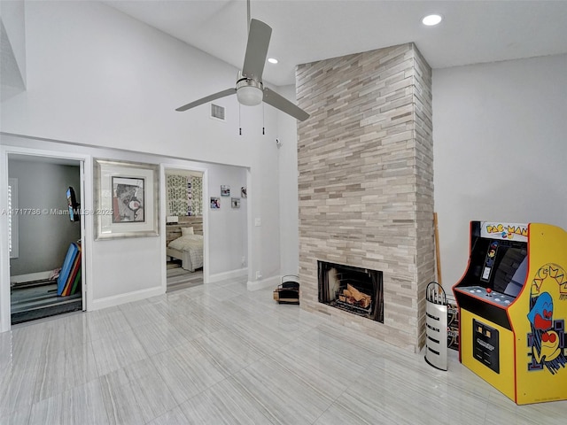 living room with ceiling fan, lofted ceiling, and a tiled fireplace