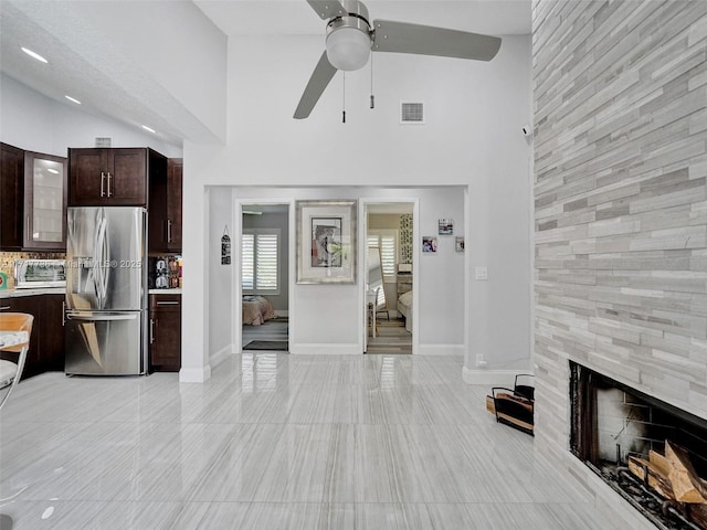 living room featuring ceiling fan, a fireplace, and vaulted ceiling