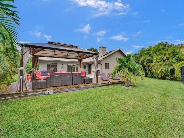 rear view of house featuring a gazebo, an outdoor living space, a deck, and a yard