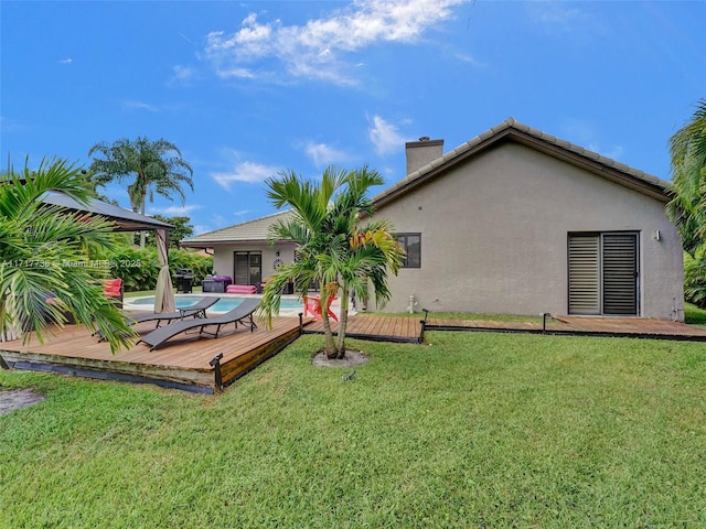 rear view of house featuring a lawn and a pool side deck