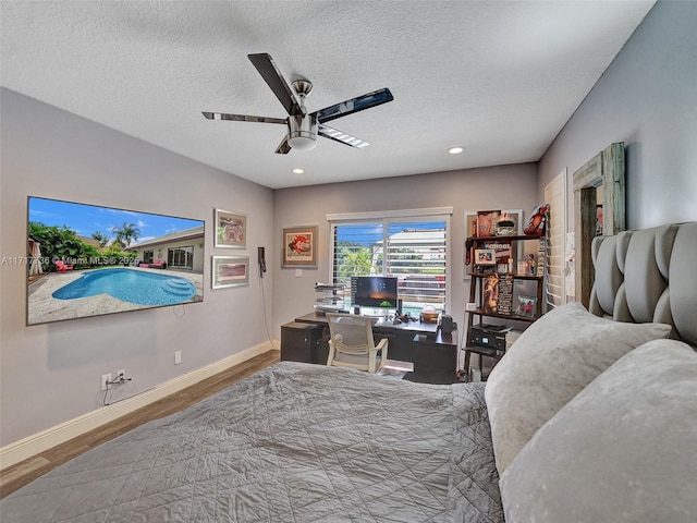 bedroom with ceiling fan, wood-type flooring, and a textured ceiling