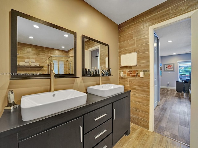 bathroom with vanity, an enclosed shower, and tile walls