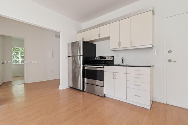 kitchen with white cabinets, light wood-type flooring, and appliances with stainless steel finishes