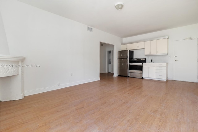 kitchen with white cabinets, appliances with stainless steel finishes, and light hardwood / wood-style floors