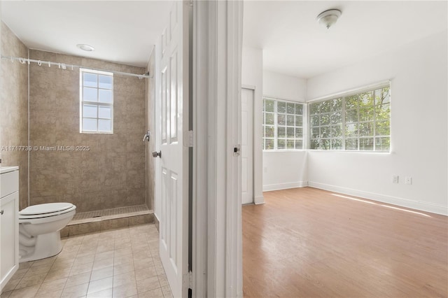 bathroom with tile patterned flooring, a tile shower, vanity, and toilet