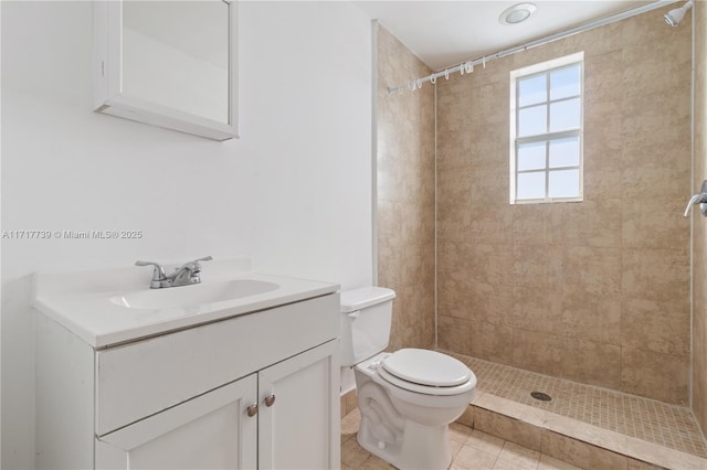 bathroom with tile patterned flooring, vanity, toilet, and a tile shower