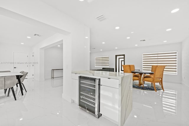 kitchen with white cabinets, wine cooler, plenty of natural light, and light stone counters