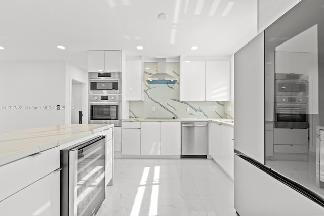 kitchen with appliances with stainless steel finishes, tasteful backsplash, beverage cooler, wall chimney range hood, and white cabinets