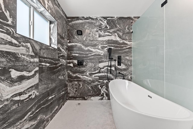 bathroom featuring a washtub and tile walls