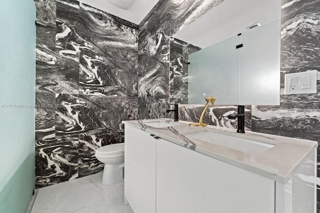 bathroom with vanity, tile walls, and toilet