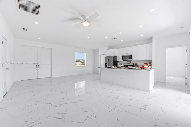 kitchen featuring white cabinets, a center island with sink, sink, light stone countertops, and appliances with stainless steel finishes