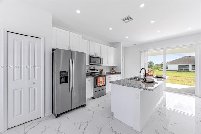 kitchen with white cabinets, sink, light stone countertops, an island with sink, and stainless steel appliances