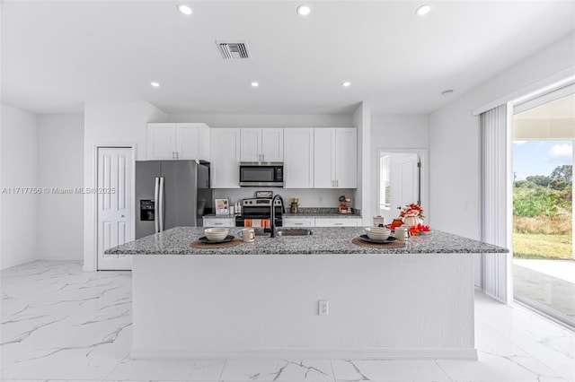 kitchen featuring stone counters, white cabinetry, an island with sink, and stainless steel appliances