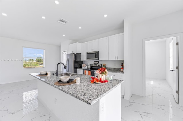 kitchen featuring sink, light stone countertops, an island with sink, appliances with stainless steel finishes, and white cabinetry