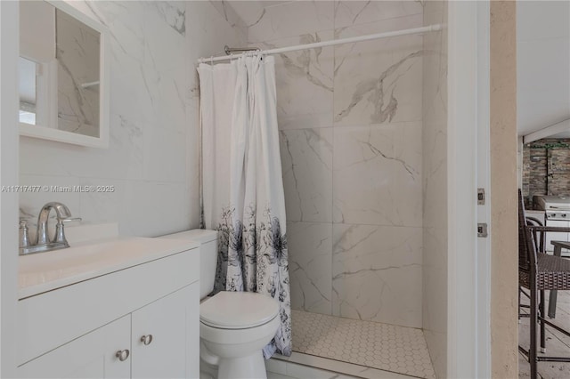 bathroom featuring vanity, toilet, walk in shower, and tile walls